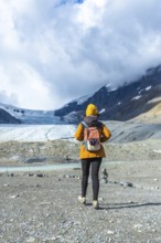 Hiker walking on the rocky terrain towards the athabasca glacier in jasper national park, alberta,