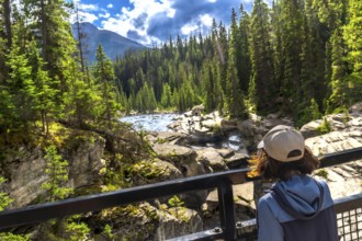 Female tourist admiring the impressive mistaya canyon with its rock formations, lush forest, and