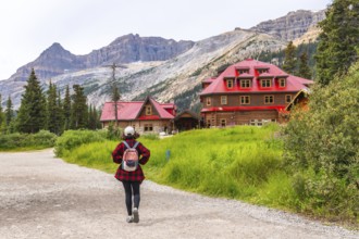 Female tourist walking on a gravel path towards the historic num ti jah lodge at bow lake in the