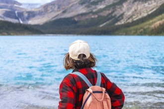 Young hiker with backpack and cap enjoying the breathtaking view of bow lake and surrounding