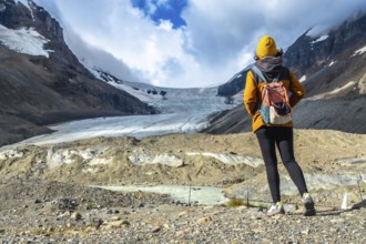 Female tourist with backpack admiring the breathtaking view of athabasca glacier in jasper national