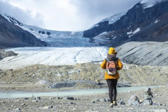 Female tourist with backpack walking towards the athabasca glacier in jasper national park,