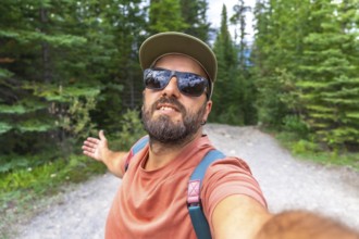 Bearded tourist with sunglasses and cap taking a selfie with arms outstretched at mistaya canyon in