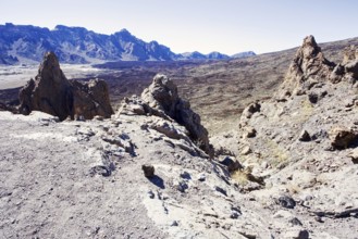 Rough volcanic landscape with rocky mountains in the background under clear sky, Pico del Teide