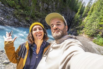Happy couple of hikers taking a selfie at the turquoise river along the ci fuentes path waterfall