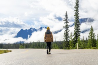 Tourist walking along the scenic icefields parkway, surrounded by majestic mountains and lush