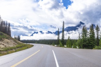 Scenic highway winds through a majestic mountain range, offering breathtaking views of the canadian