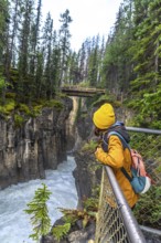 Hiker observing the impressive sunwapta falls from a viewpoint in jasper national park, surrounded