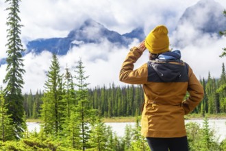 Hiker shielding her eyes while admiring the breathtaking vista of the canadian rockies along the