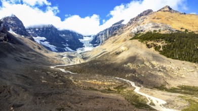 Sun shining on athabasca glacier in the canadian rockies with clouds and blue sky reflecting on