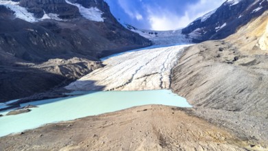 Athabasca glacier is melting into a vibrant turquoise lake, showing the effects of climate change