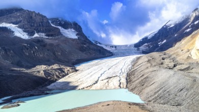 Athabasca glacier flows down from the columbia icefield, melting into a turquoise lake, surrounded