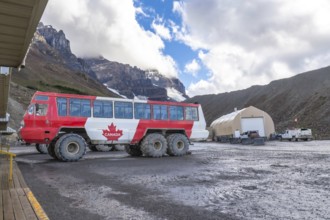 Large all terrain bus with a canadian flag parked near athabasca glacier in columbia icefield,