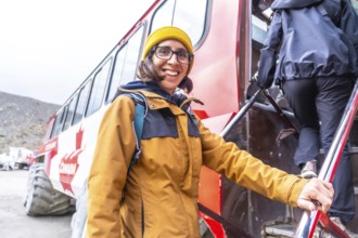 Smiling female tourist stepping off an ice explorer bus at athabasca glacier in jasper national