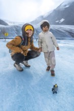Mother and her child are enjoying a memorable adventure on the athabasca glacier, surrounded by the