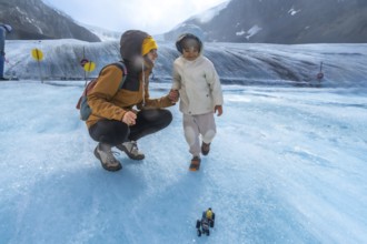 Mother and child enjoying playful moments on the athabasca glacier, with a toy vehicle in the