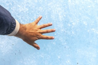 Hand of a tourist touching the millennial ice of athabasca glacier in the columbia icefield, inside