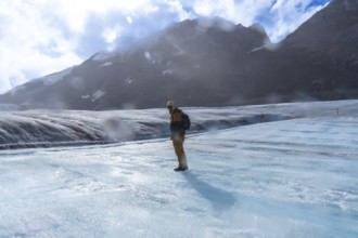 Hiker wearing winter clothing and a backpack, standing on the vast icy expanse of athabasca glacier
