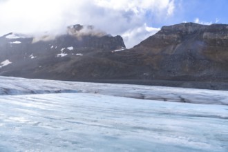 Tourists walking on the athabasca glacier in jasper national park, surrounded by mountains and