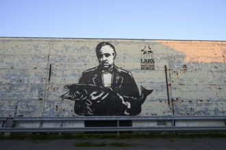 A large mural shows Marlon Brando in the Godfather holding a fish. Mural by street artist Pobel.