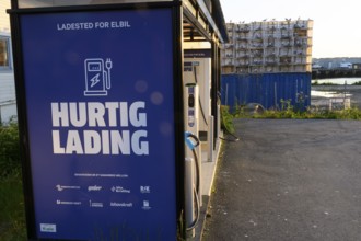 Electric car charging station at Vardöä harbour in Norway at sunset with blue sky and adjacent