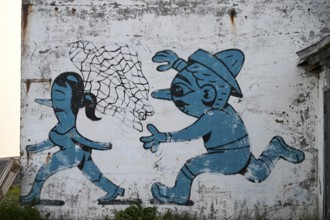 Mural in which a fisherman catches a woman with a net. By Husk Mit Navn. Vardö street art