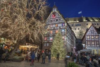 Christmassy illuminated square with the historic Pilate House with advent calendar, in the evening