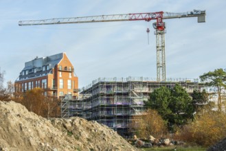 Construction site with completed high-rise building, house under construction and construction