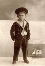 Historical cabinet card, boy in sailor suit against maritime studio backdrop with sailing ship,
