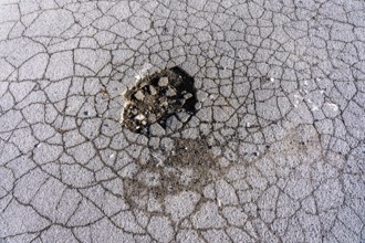 Pothole, asphalt surface, floor, with many small cracks, roadway, parking lot