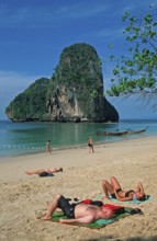 Rocks in the sea, people and longtail boats on Pranang Cave beach, two years in front of the