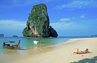 Rocks in the sea, people and longtail boat on Pranang Cave beach, two years in front of the
