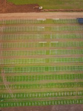 Aerial view of green fields with beginning solar plant construction and agricultural patterns,
