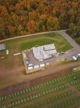 Autumn aerial view of a building materials warehouse with surrounding fields and an adjacent road,