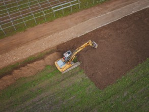 Aerial view of an excavator working a field and moving soil, Energiewende, construction of PV open