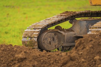Detailed view of the chains of an excavator covered with soil, on a construction site,