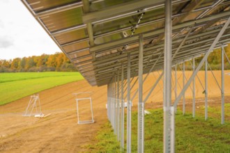 Metal structure for solar panels in a field next to an autumn forest, energy revolution,