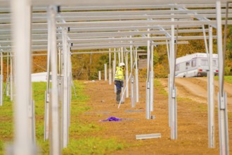 Workers with motorhome in the background working on the construction of solar panels in a field,