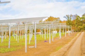 Extensive site with metal structures for solar panels and autumn sky, energy revolution,