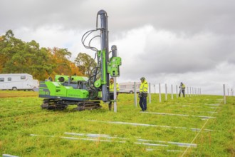 A drilling rig is operated by workers on a green field in autumn, Energiewende, construction of PV