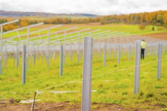 Metal poles along a field under cloudy sky with autumn landscape in the background, Energiewende,