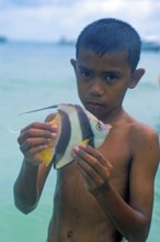Boy with a tropical fish on Ko Phi Phi Don, two years in front of the tsunami, Thailand, December