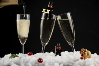 Three champagne glasses with lucky charms for New Year in the snow