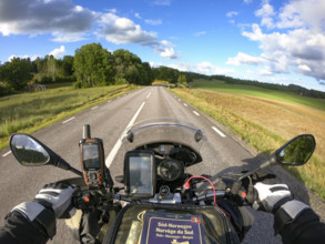Motorcycle ride on a deserted road through a green landscape under blue sky with clouds