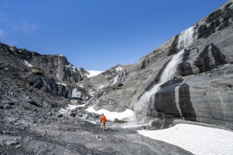 Tourist standing at a glacier stream, glacier ice and waterfall, Worthington Glacier State