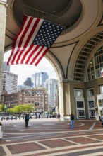 American flag fluttering, distinctive archway, Boston Harbor Hotel, Rowes Wharf, passers-by,