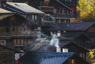 Smoke rises over the roofs of old wooden houses in Vissoie, Val d'Anniviers, Valais Alps, Canton of