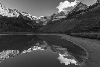 The Moiry glacier and mountain peaks are reflected in Lac de Chateaupre, black and white photo, Val