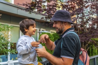 Father and son sharing a joyful bonding moment in vancouver, as dad opens a water bottle for his