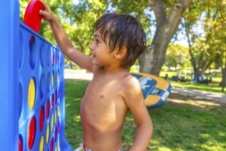 Happy child playing connect four in a vibrant park in kamloops, british columbia, soaking up the
